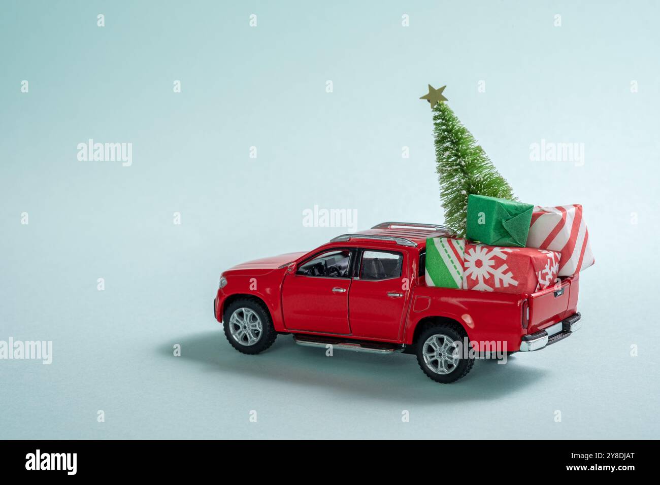 Ein roter Truck ist mit einem Weihnachtsbaum und Geschenken dekoriert. Die Szene ist festlich und fröhlich, wobei der Truck im Mittelpunkt steht Stockfoto