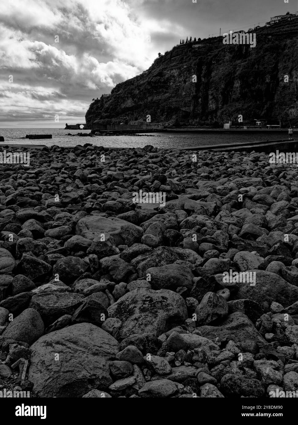 Felsige Küste unter dramatischen Wolken mit hoch aufragenden Klippen in Madeira in Schwarz-weiß Stockfoto