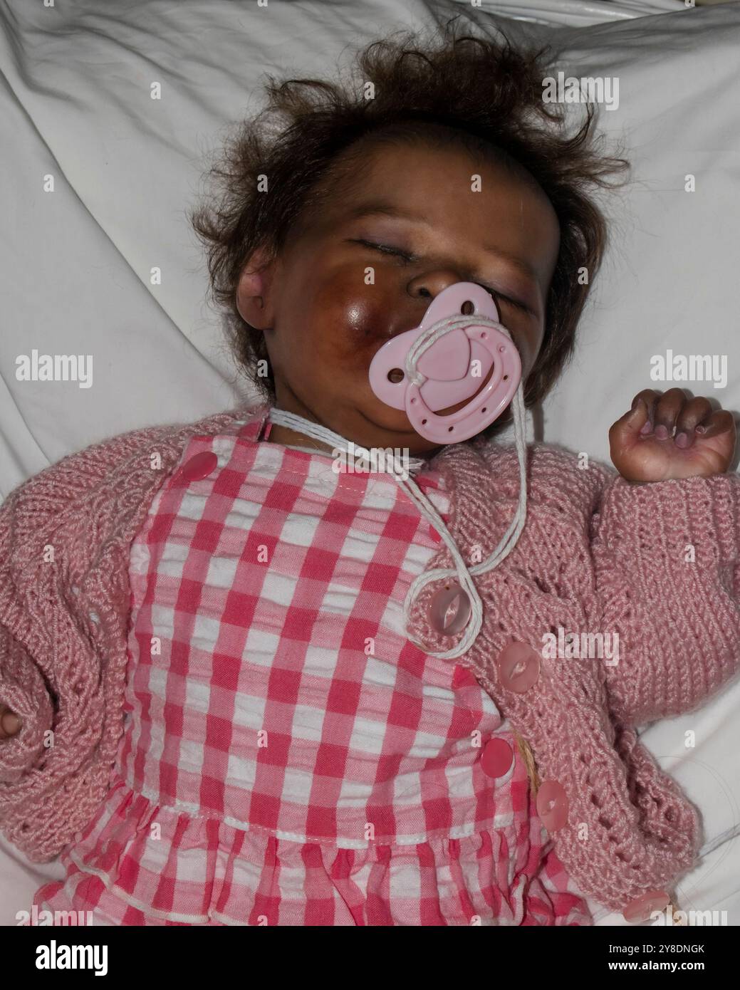 Niedliche, wiedergeborene Babypuppe in rosa Kleidung, realistische Puppe, die im Bett schläft Stockfoto