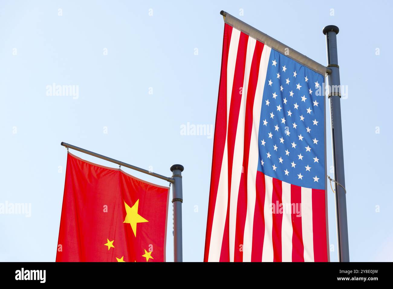 Verschiedene Nationalflaggen fliegen auf Fahnenmasten vor blauem Himmel, chinesische Flagge, amerikanische Flagge Stockfoto