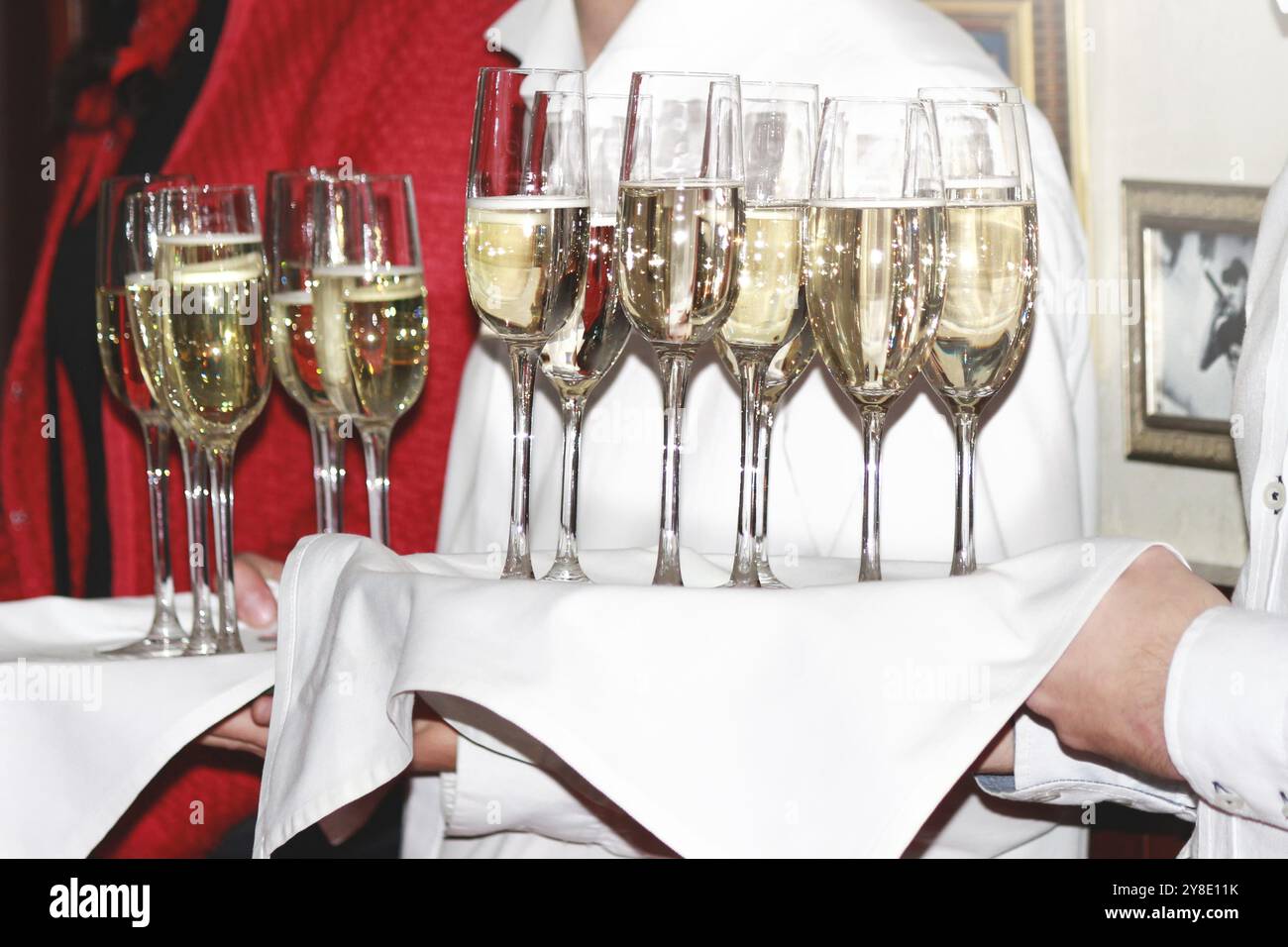 Ein Kellner überreicht den Gästen auf einer Firmenfeier Sektgläser. Getränke Stockfoto
