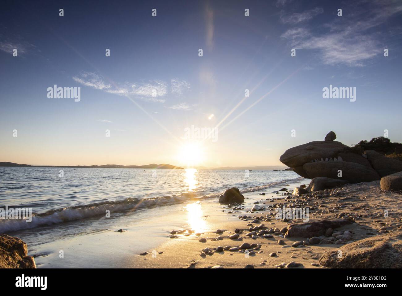 Blick durch Felsen an einem Sandstrand in den Sonnenuntergang. Landschaft mit Blick auf den Horizont über dem weiten Meer an der Küste von Ouranoupoli, Thessaloni Stockfoto