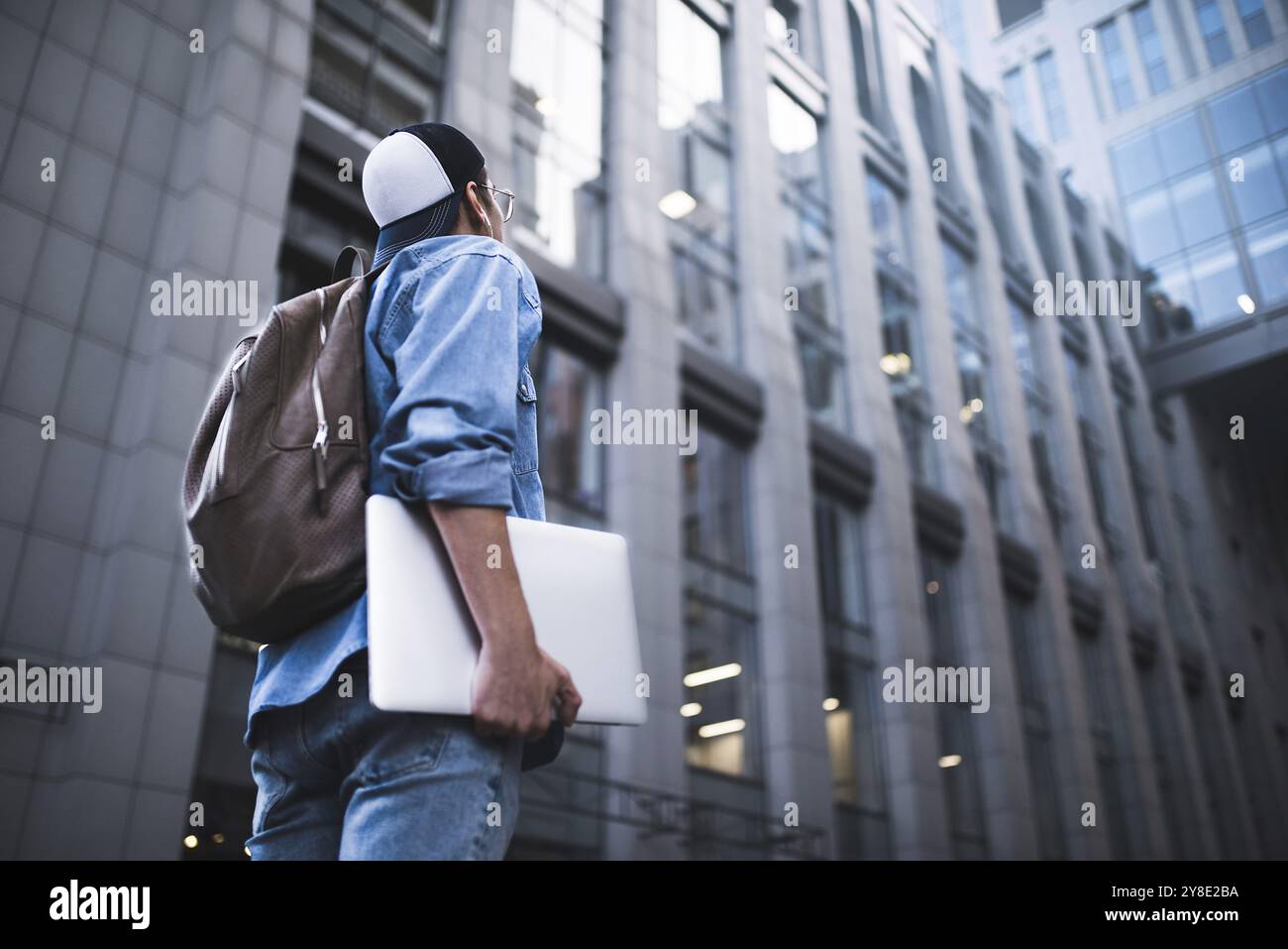 Outdoor Portrait von hübscher junger männlicher Student mit Rucksack an Gebäude Hintergrund auf der Straße, während seine Kollegen warten. Unternehmer Stockfoto