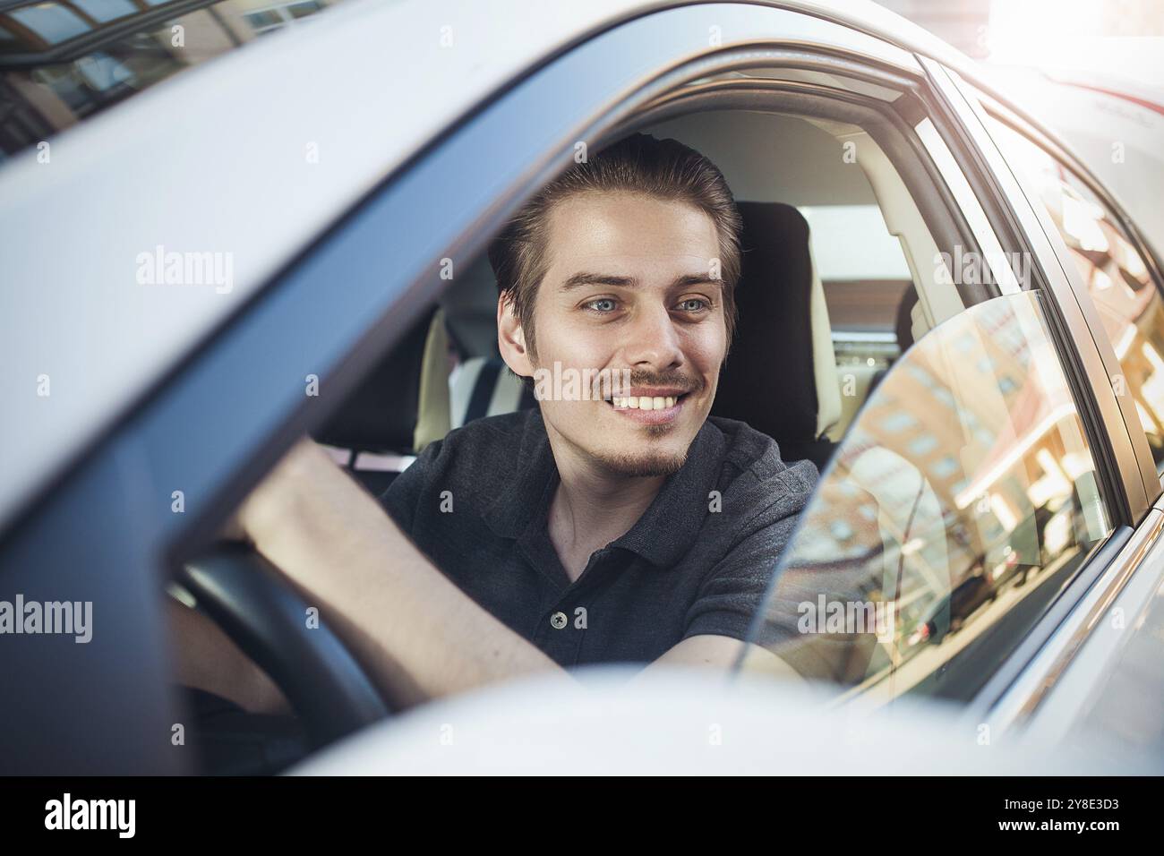 Genießen Sie die Fahrt. Bild eines hübschen jungen Mannes, der im Auto sitzt Stockfoto