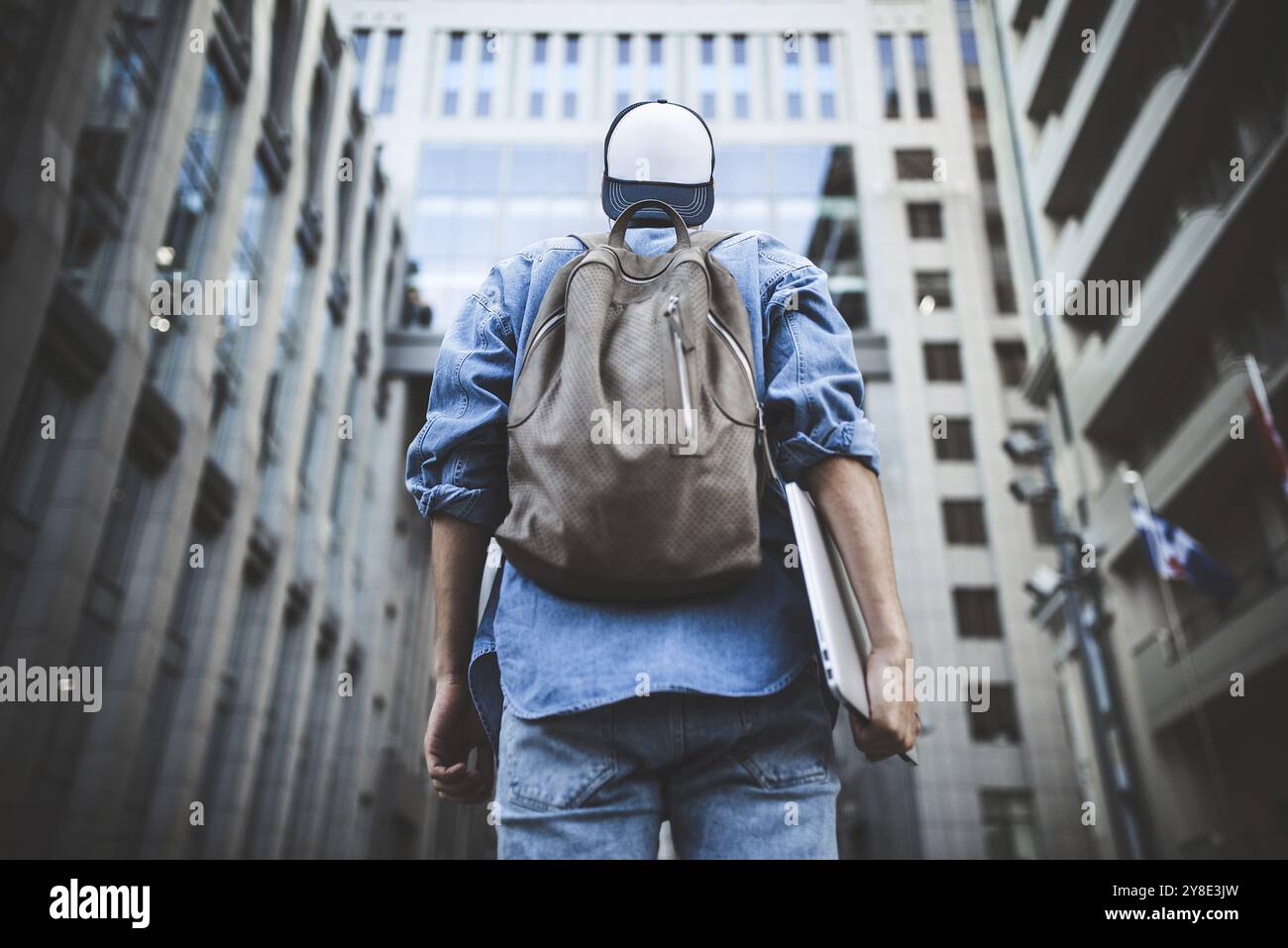 Outdoor Portrait von hübscher junger männlicher Student mit Rucksack an Gebäude Hintergrund auf der Straße, während seine Kollegen warten. Unternehmer Stockfoto