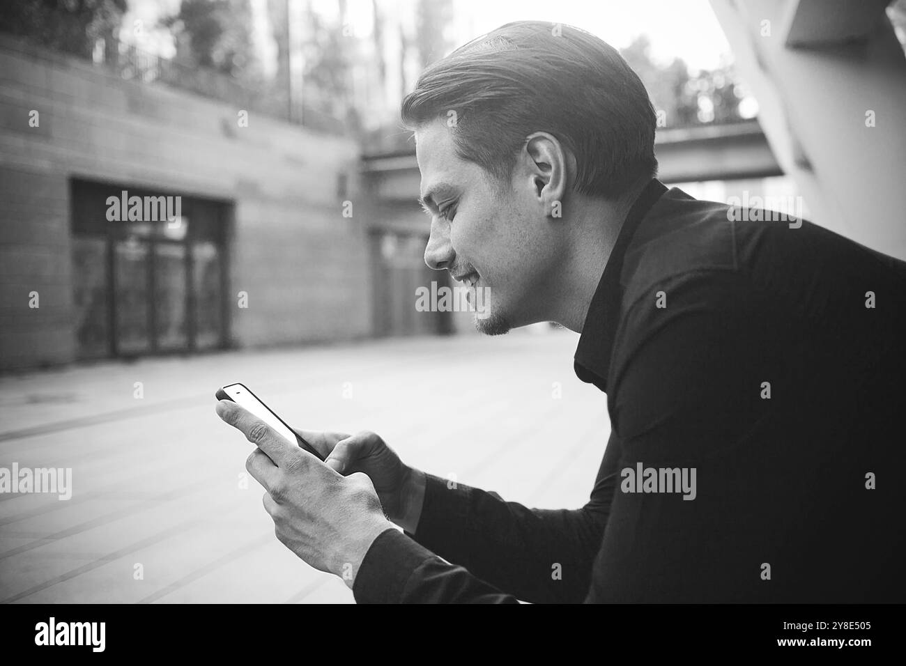 Lächelnder Geschäftsmann benutzt ein Smartphone auf der Straße Stockfoto