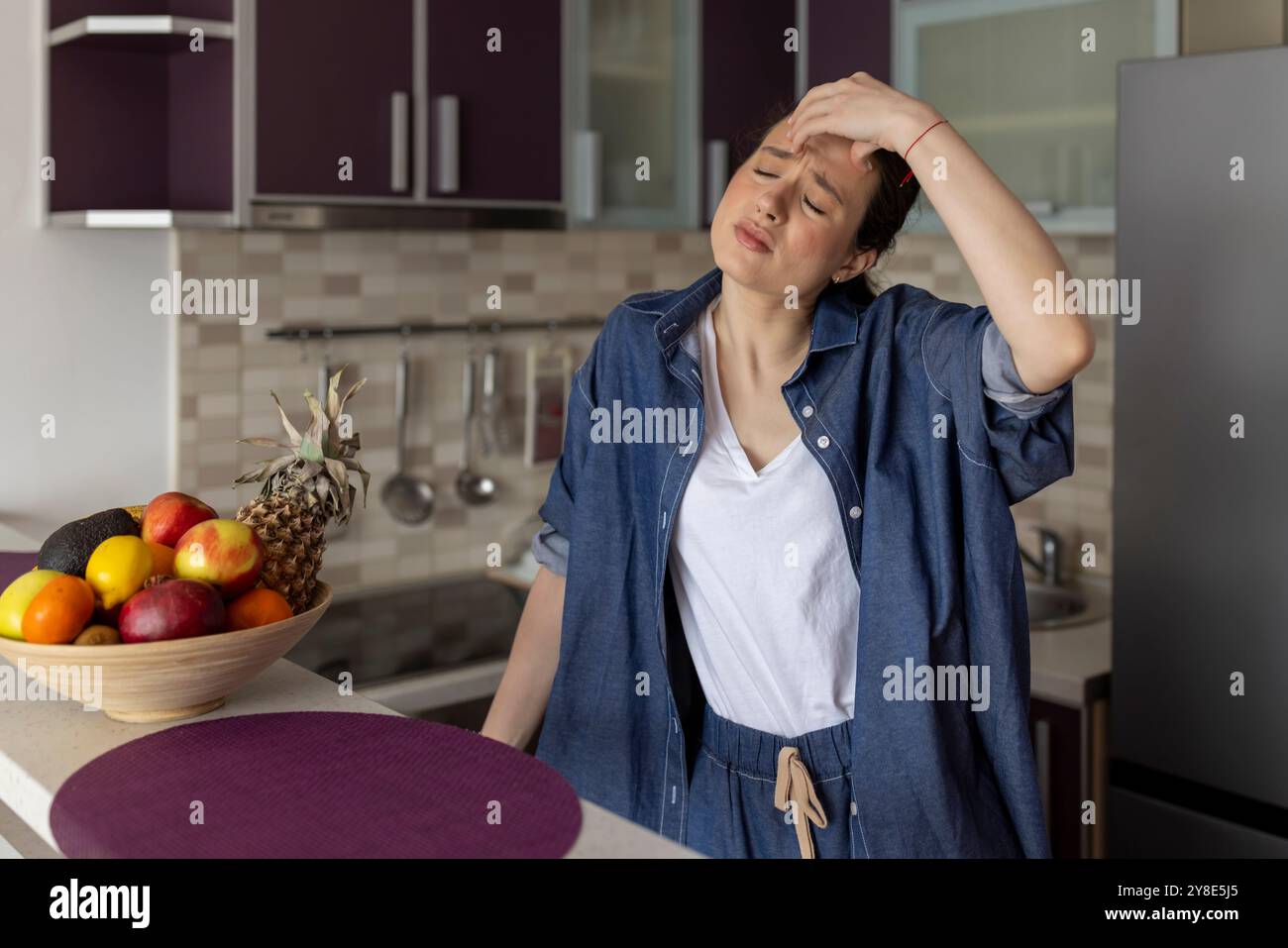 Frau mit Kopfschmerzen und Kopfschmerzen in der Küche zu Hause Stockfoto