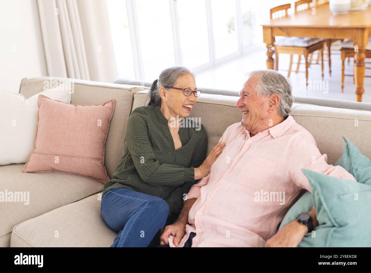 Glückliches Seniorenpaar, das auf dem Sofa sitzt und lächelt Stockfoto