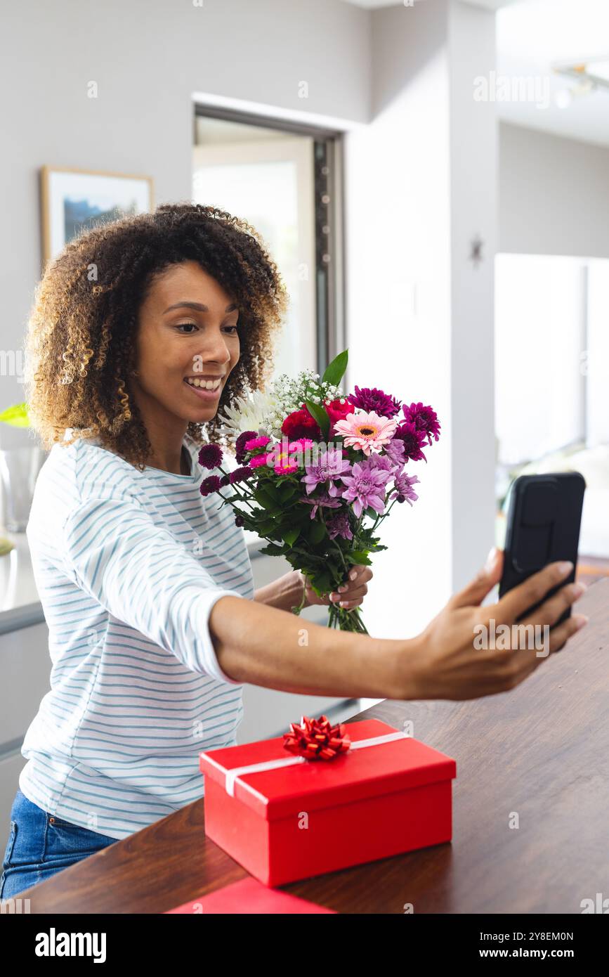 Eine birassische Frau macht zu Hause ein Selfie mit Blumen für ihre Tochter Stockfoto