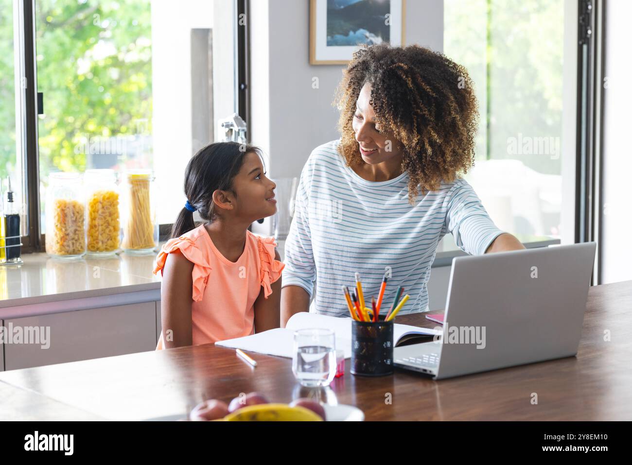 Die birassische Mutter hilft einer kleinen Tochter bei der Schularbeit zu Hause Stockfoto