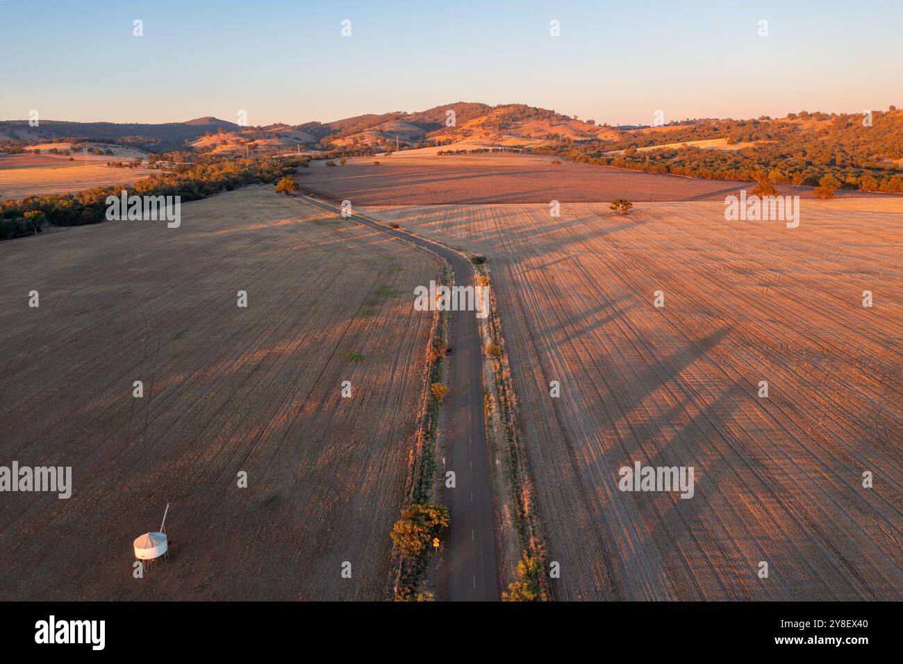 Aus der Vogelperspektive einer Landstraße, die durch trockenes Ackerland mit Schatten am frühen Morgen in Wilmington in South Australia führt, Stockfoto