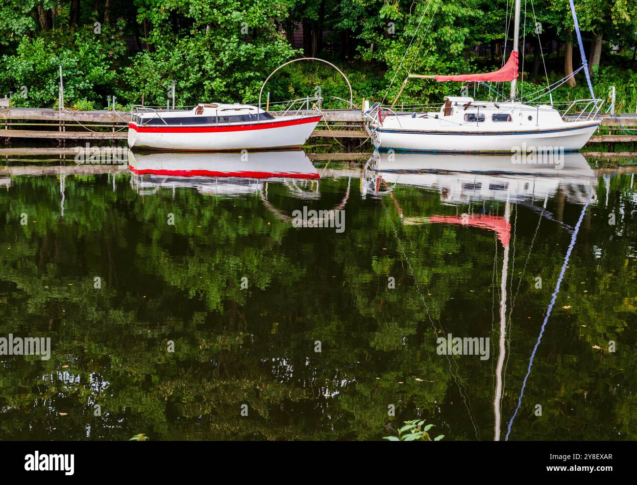 Antrim, County Antrim Northern Ireland 20. September 2024 - Boote, die am Ufer des Sixmile Water nahe Lough Neagh mit einer Reflexion des Mastes verankert sind. Stockfoto