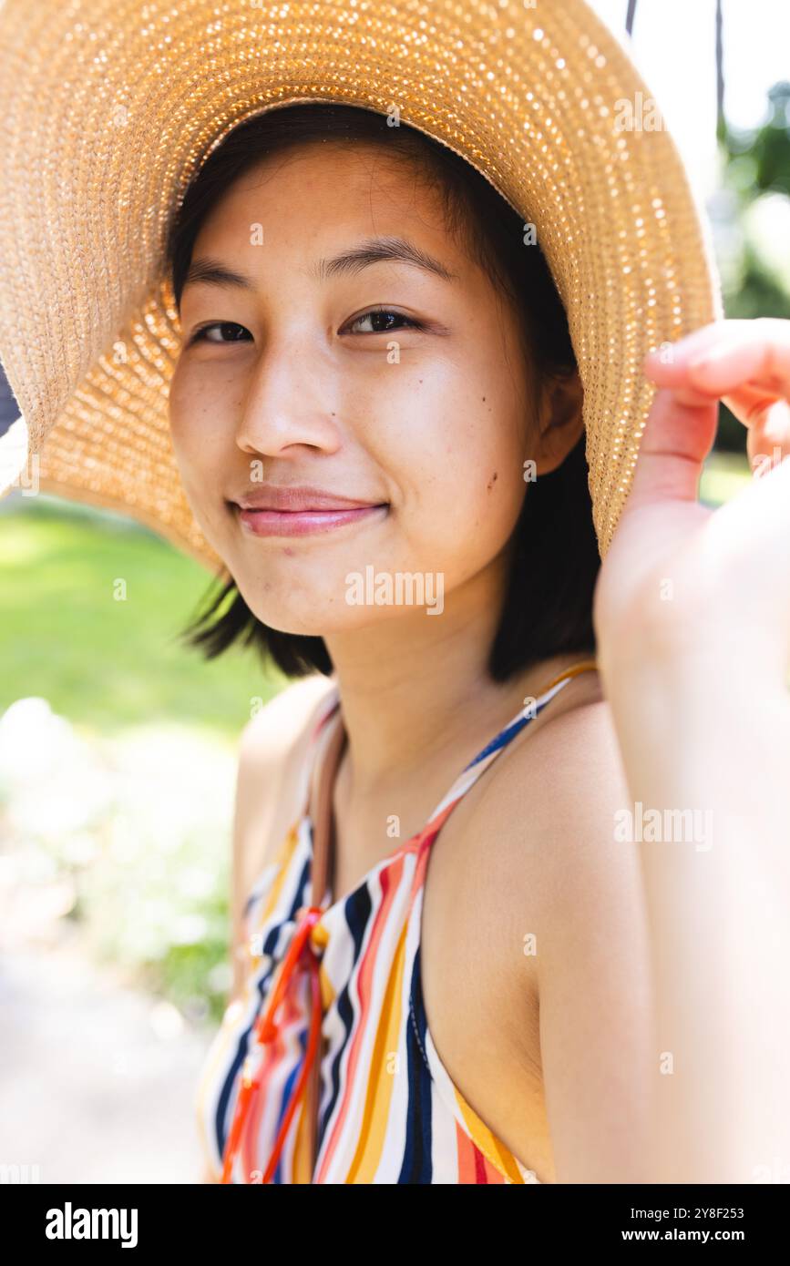 Porträt einer glücklichen asiatischen Frau mit kurzen Haaren, die im Garten zu Hause einen Sonnenhut trägt Stockfoto