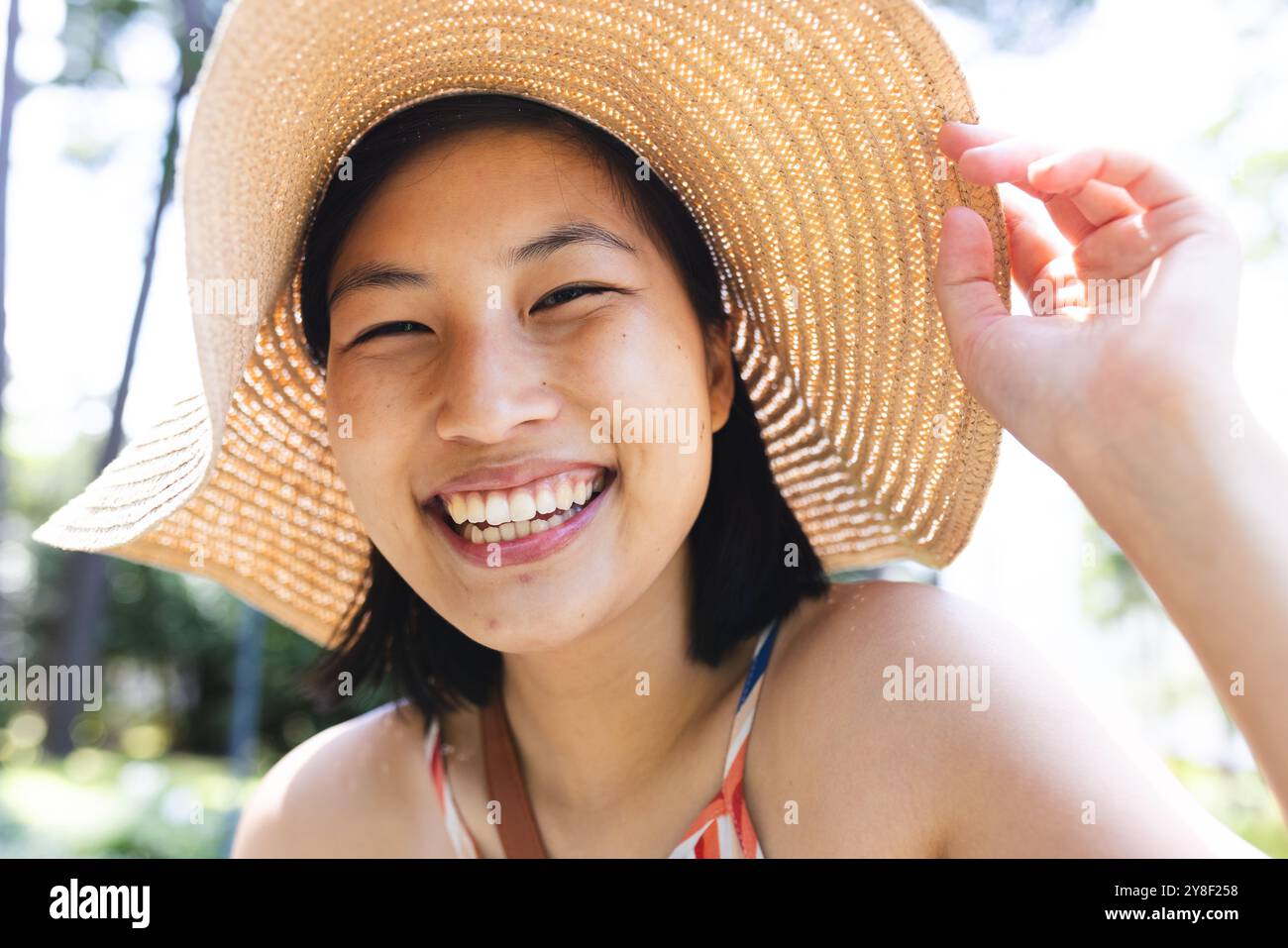 Porträt einer glücklichen asiatischen Frau mit kurzen Haaren, die im Garten zu Hause einen Sonnenhut trägt Stockfoto