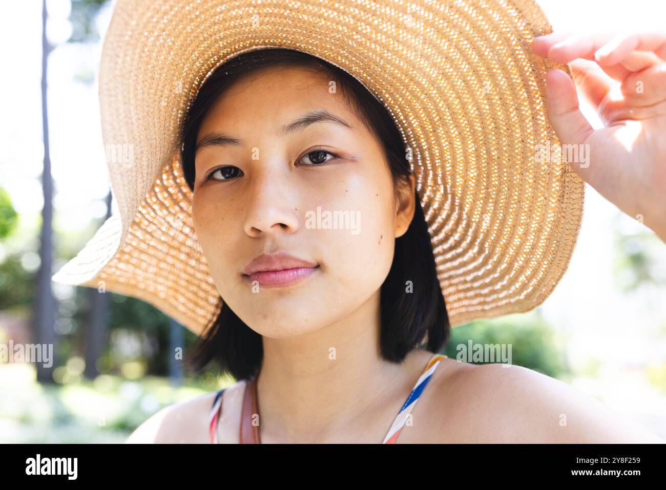 Porträt einer asiatischen Frau mit kurzen Haaren mit Sonnenhut im Garten zu Hause Stockfoto