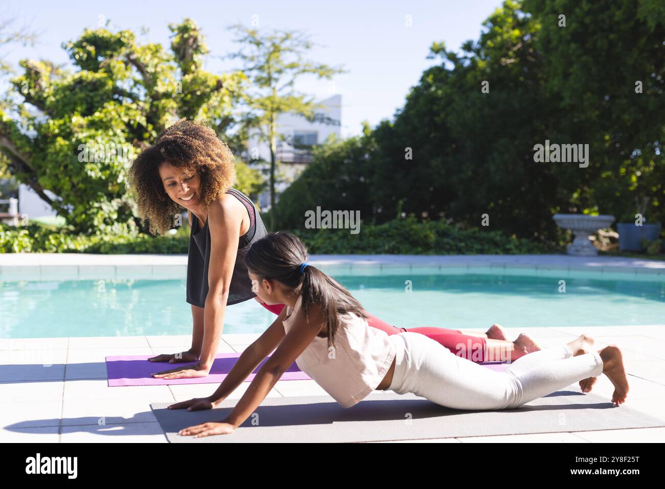 Birassische Mutter unterrichtet einer Tochter im Freien Yoga Stockfoto