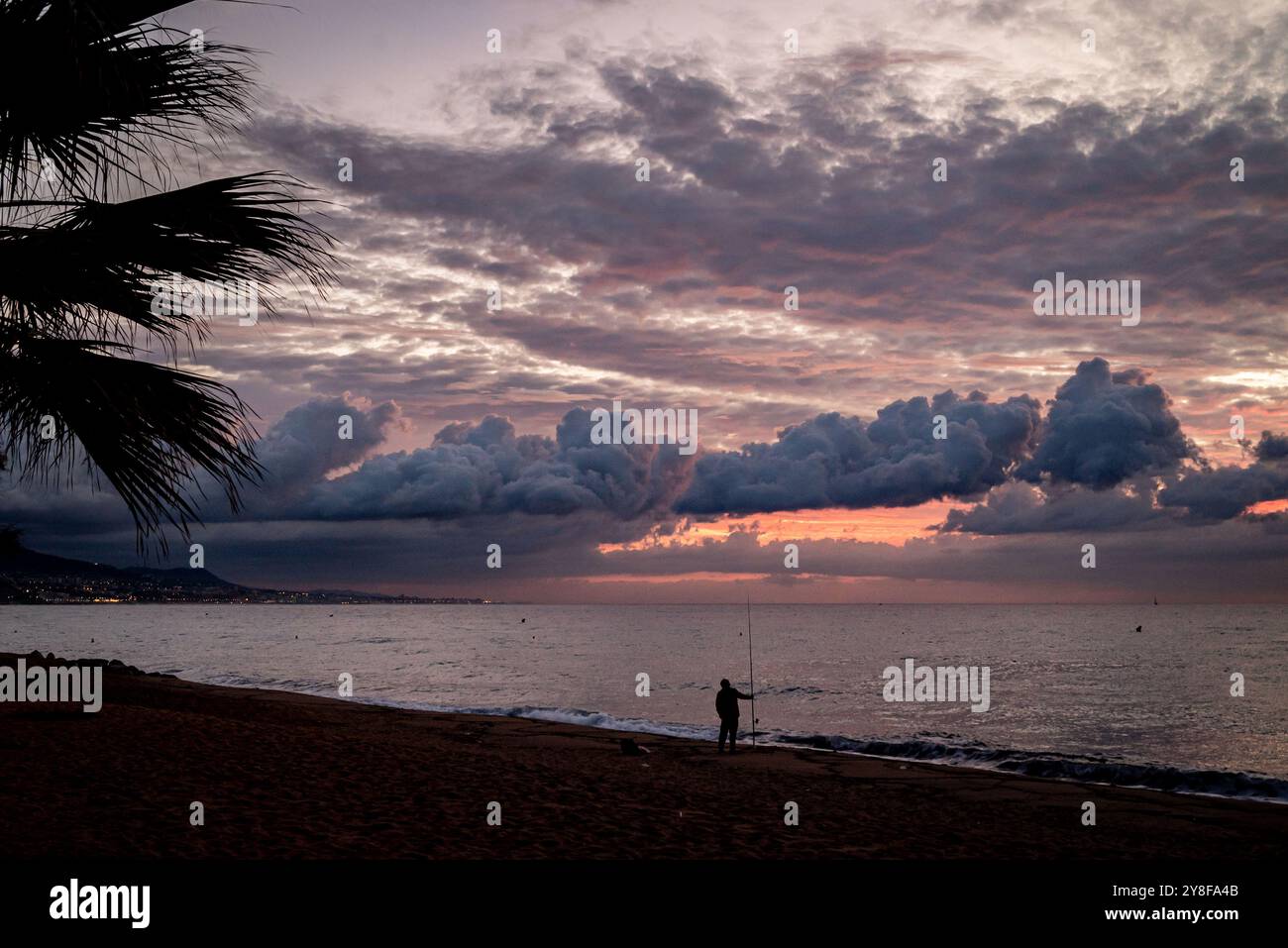 Badalona, Spanien. 5. Okt. 2024: Ein Mann steht mit einer Angelrute bei Sonnenaufgang am Strand in Badalona, Provinz Barcelona. Bild: Jordi Boixareu/Alamy Live News. Stockfoto