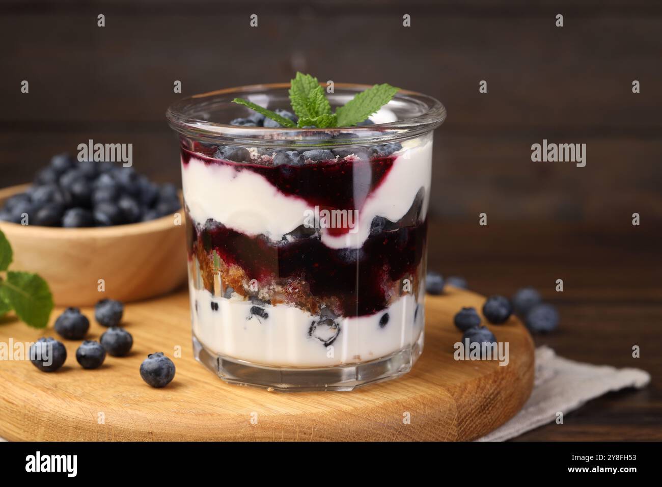 Leckeres kleines Dessert. Heidelbeeren, Biskuitkuchen und Schlagsahne im Glas auf Holztisch Stockfoto