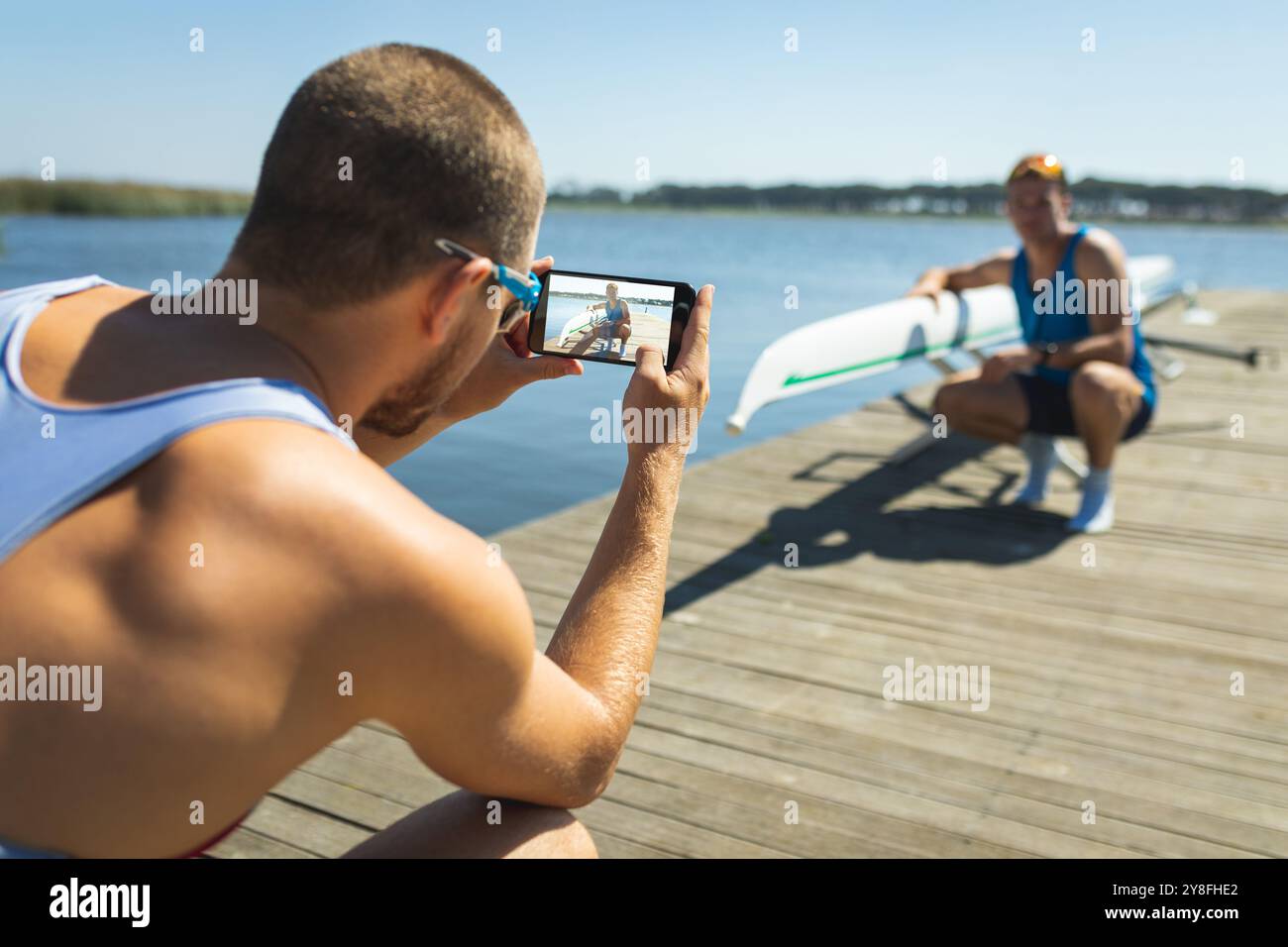 Männlicher Ruderer, der mit dem Smartphone seines Freundes fotografiert Stockfoto