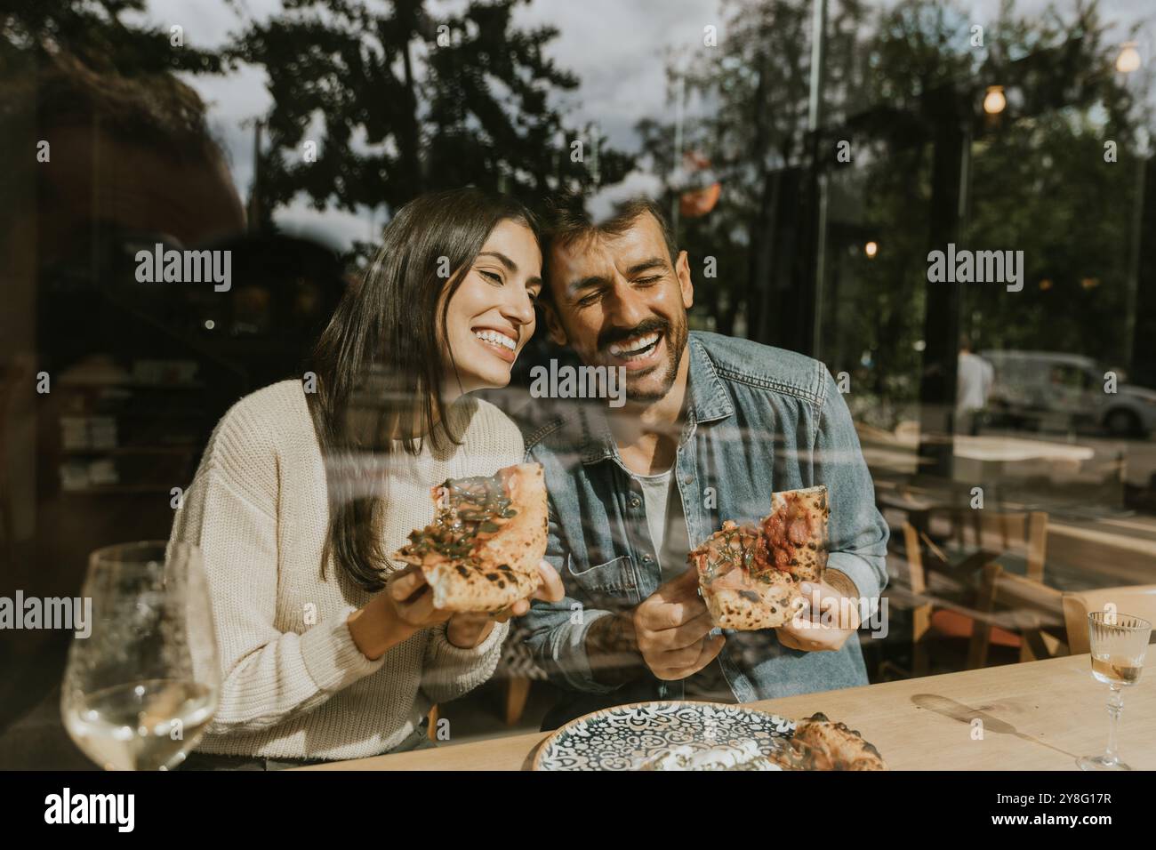 Ein Paar genießt in einem charmanten Café, umgeben von hellem, luftigem Ambiente und guter Atmosphäre, köstliche Pizzabäcke Stockfoto