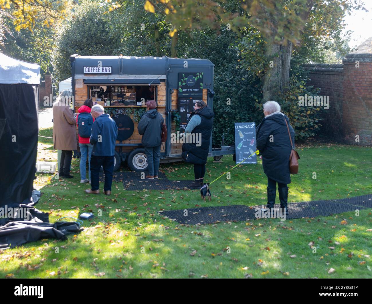 Leute, die in der Herbstsonne an einem Pop-up-Stand um Essen warteten Stockfoto