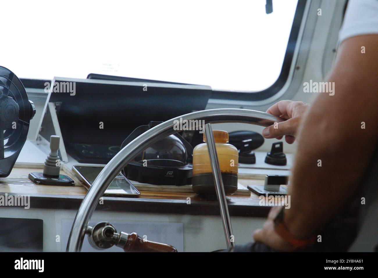 Skipper am Helm: Das Boot vom Innenraum aus steuern Stockfoto