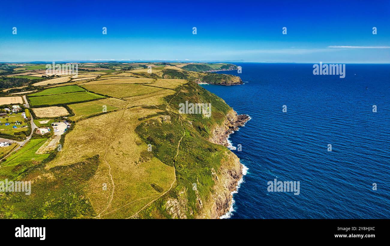 Aus der Vogelperspektive auf eine zerklüftete Küste mit grünen Feldern und Klippen mit Blick auf das blaue Meer. Die Landschaft bietet eine Mischung aus Ackerland und natürlichem Scener Stockfoto