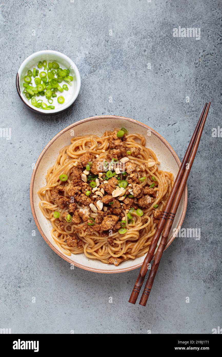 Dan Dan Dan Nudeln serviert mit Essstäbchen und grünen Zwiebeln, traditionelles chinesisches Sichuan-Gericht Stockfoto