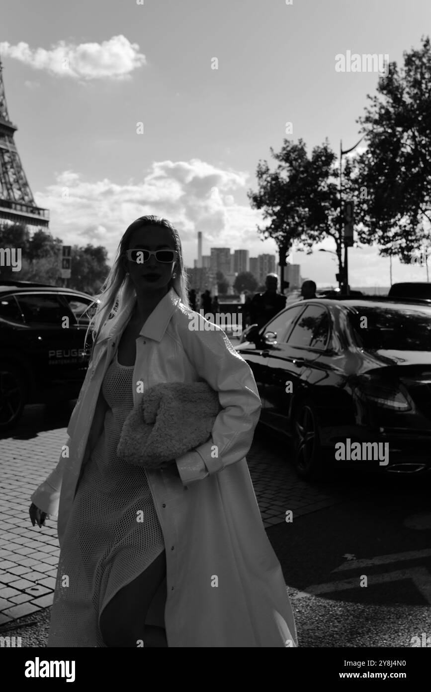 Eine eingeladene Person in einem ganz weißen Outfit mit einem langen Mantel und einer Pelzhandtasche für die Elie Saab Show auf der Paris Fashion Week SS25 Stockfoto