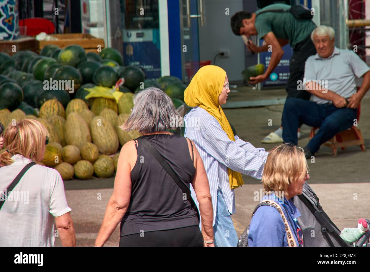 Taschkent, Usbekistan;16. September 2024: Eine muslimische Frau trägt einen auffälligen gelben Hijab, während sie durch einen geschäftigen Markt in Taschkent, Usbekistan, geht. Stockfoto Taschkent, Usbekistan;16. September 2024: Eine muslimische Frau trägt einen auffälligen gelben Hijab, während sie durch einen geschäftigen Markt in Taschkent, Usbekistan, geht. Stockfoto