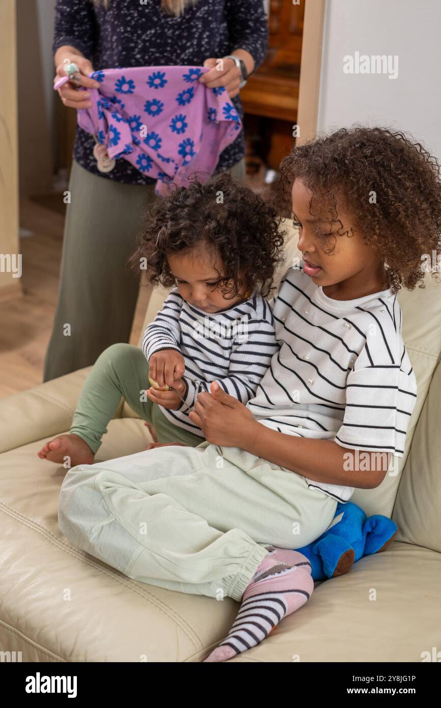 Liebevolles älteres Kind, das jüngere Geschwister zu Hause tröstet, liebevoll auf der Couch, Familienliebenskonzept Stockfoto