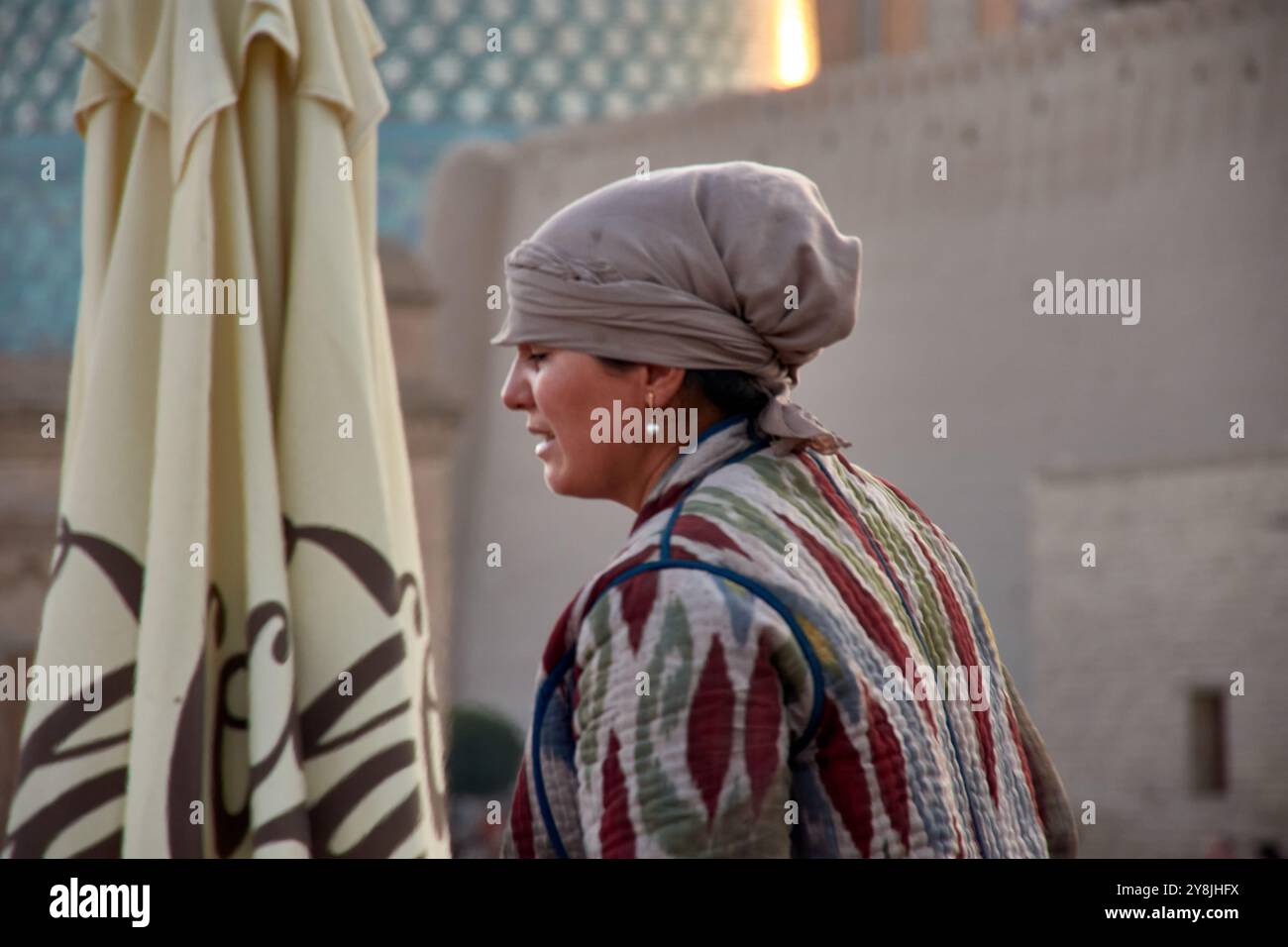 Chiwa, Usbekistan; 21. September 2024: Eine ortsansässige usbekische Frau, die traditionelles Brot in der historischen Stadt Chiwa, Usbekistan, backt. Gekleidet in einfach, traditionell Stockfoto