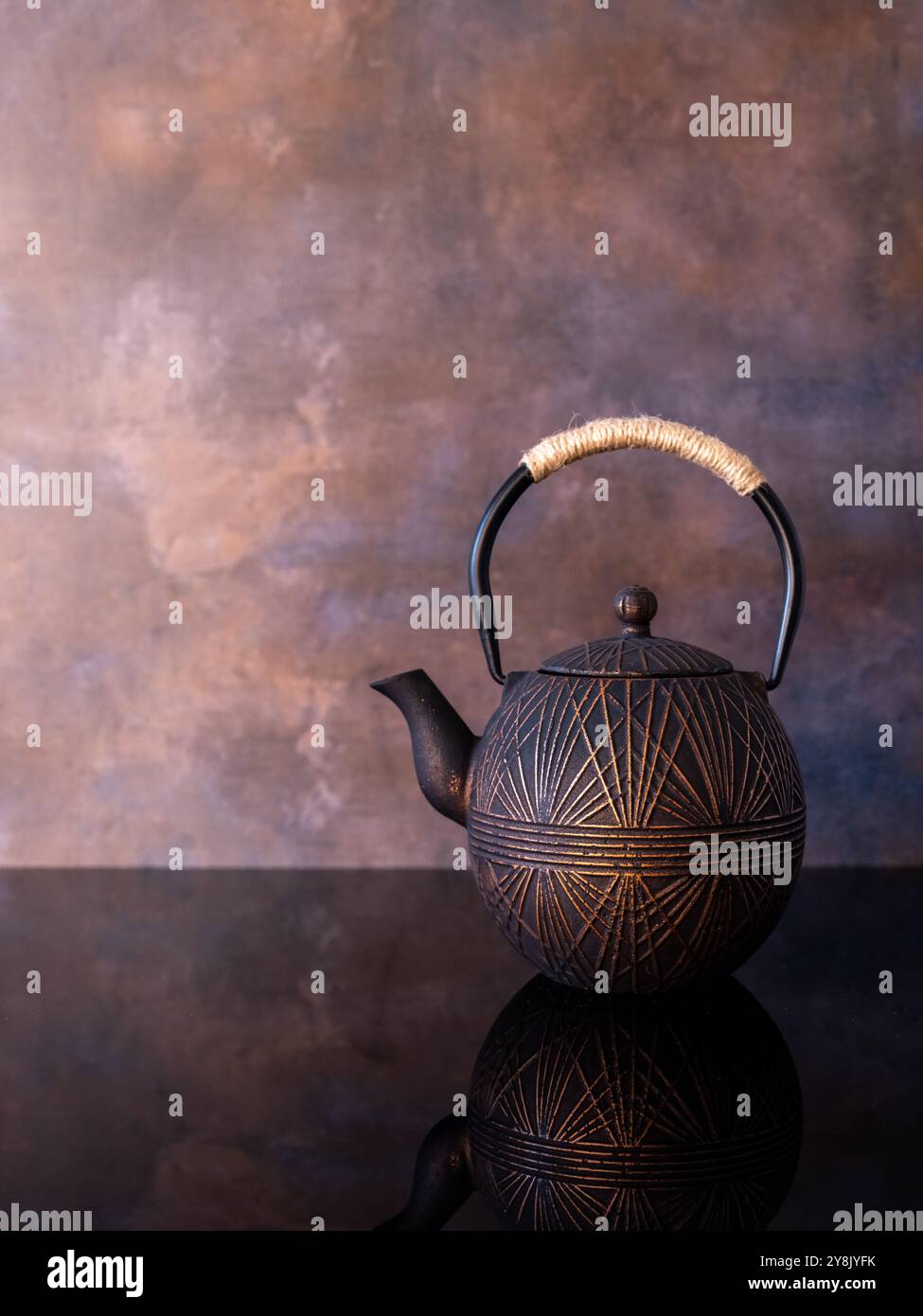 Teekessel aus Bronze, reflektiert in der Theke mit braunem Hintergrund Stockfoto