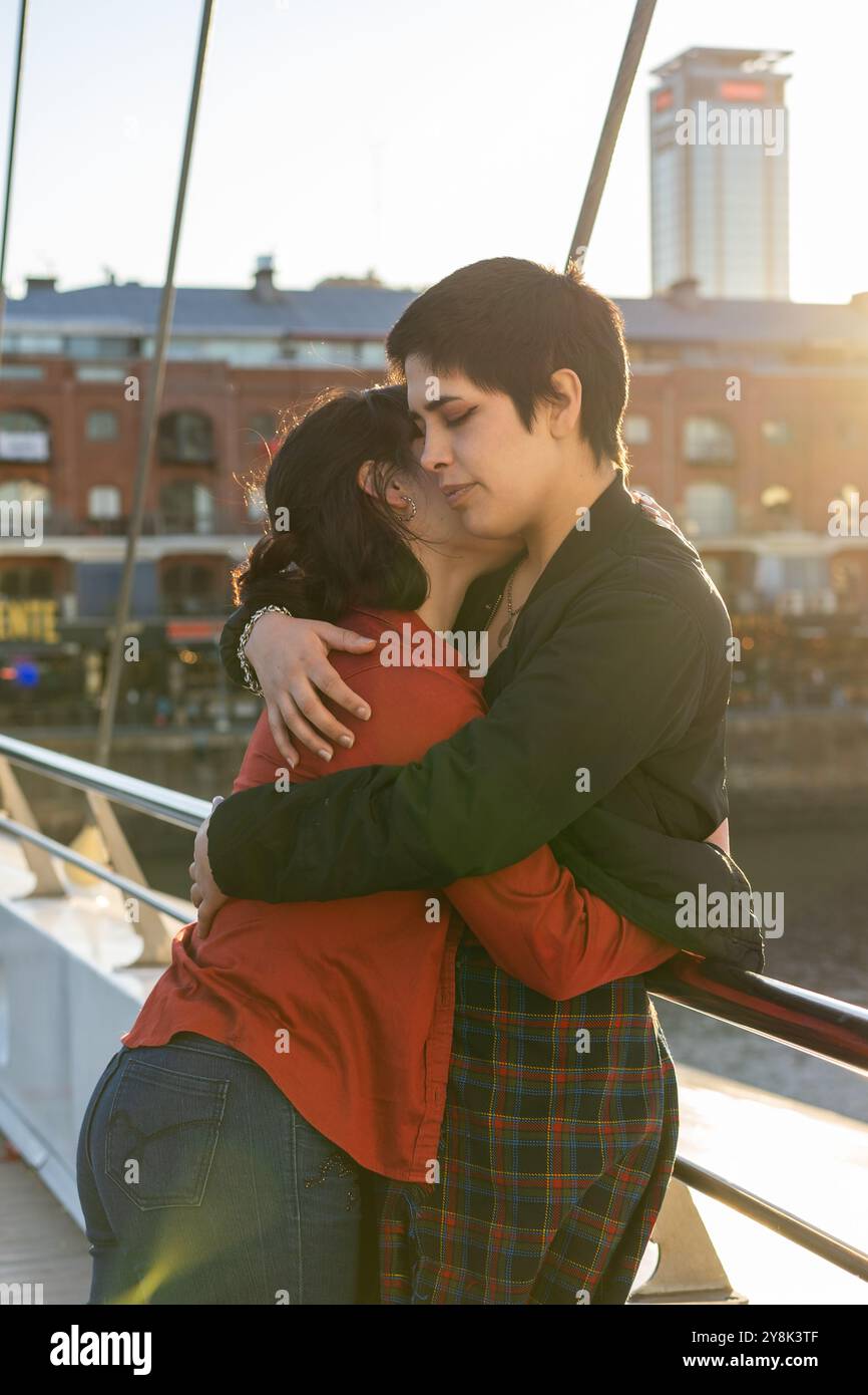 Liebevolle junge LGBT-Frauen, die sich auf einer Brücke umarmen. Stockfoto