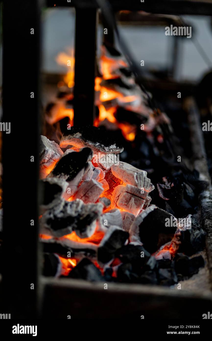 Brennender Holzkohlegrill, Feuer brennt in einem blauen Licht am Abend als Vorbereitung für Fleisch- und Fischmahlzeiten im Freien. 2024 Inhalt. Stockfoto