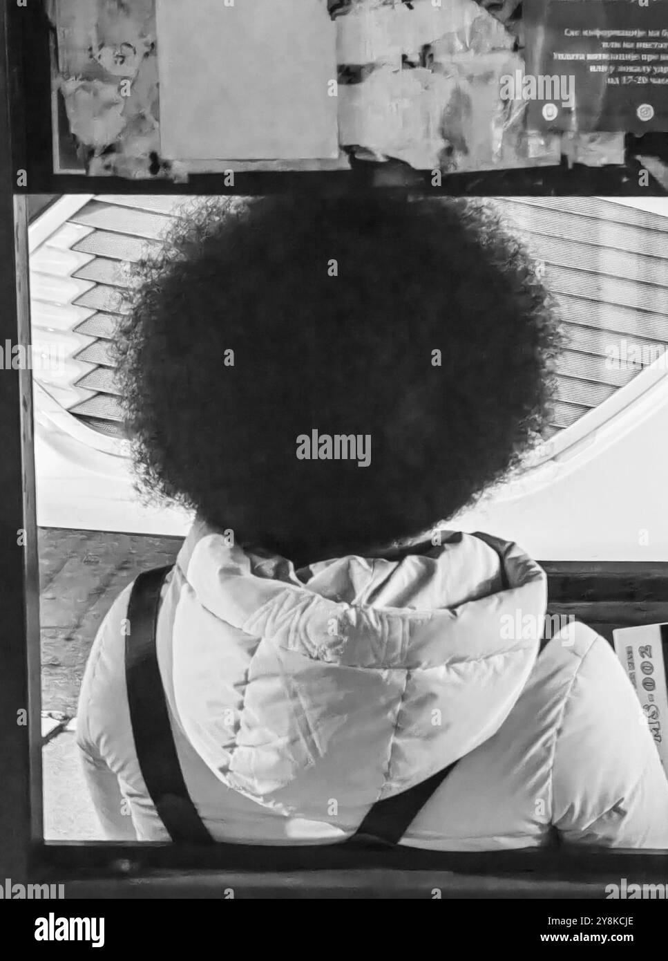 Gesichtsloses Stadtporträt: Junger Mensch mit Afro-Frisur wartet auf den Bus Stockfoto