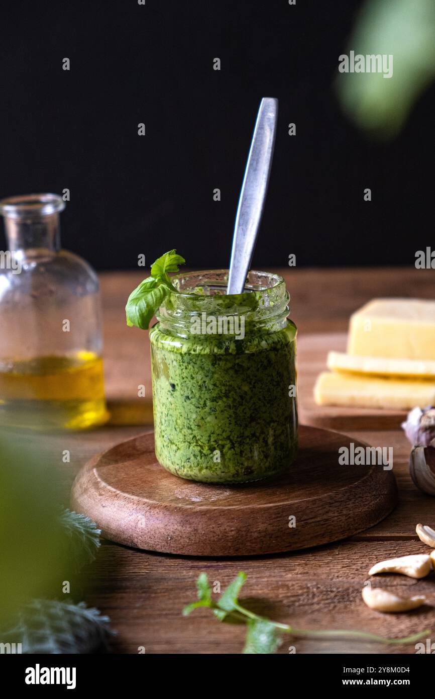 Basilikum-Pesto in einem Glas auf einem rustikalen Tisch. Vertikales Foto Stockfoto