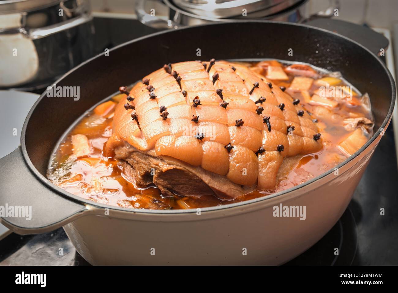 Eine festliche Mahlzeit zubereiten, Schweinebraten mit Rinde in Rautenform und mit Zehen in einem Auflauf mit Gemüse und Brühe für den Ofen Stockfoto