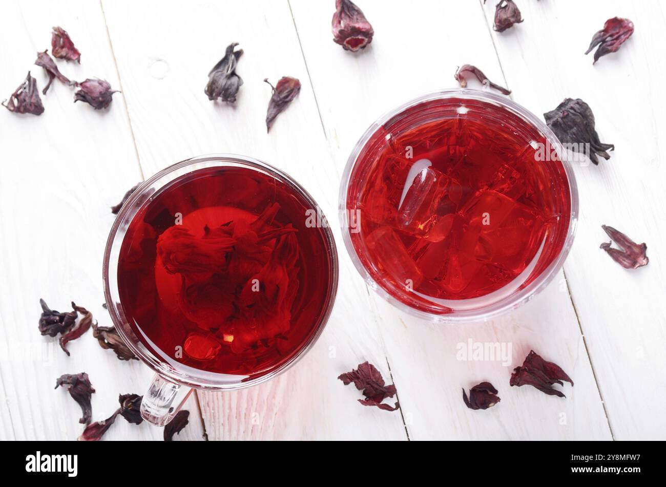 Draufsicht bei zwei Tassen mit Eis und trockenen Hibiscus Blüten auf Weiß Holztisch Hintergrund Stockfoto