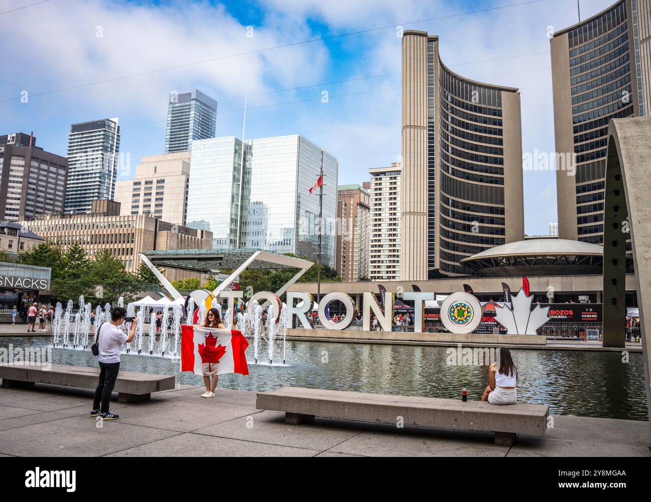 Eine junge Frau entfaltet eine kanadische Flagge auf dem Nathan Phillips Square in der Nähe des Rathauses in Toronto Stockfoto