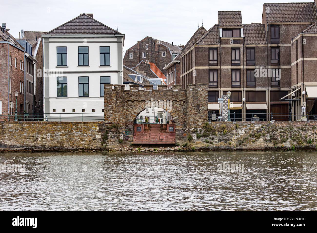 Ruinen der mittelalterlichen Mauer Waterpoortje bei Wyck am Ufer der Maas, Stadtbild mit alten und modernen Gebäuden im Hintergrund, bewölkter Tag in Maastricht, Stockfoto