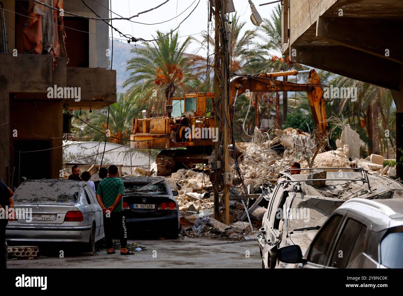 Jiyeh, Libanon. Oktober 2024. Libanesen beobachten, wie eine raupe bei der Suche nach Überlebenden im südlibanesischen Dorf Jiyeh Schutt eines flachen Gebäudes beseitigt, das von einem israelischen Luftangriff angegriffen wurde. Quelle: Stringer/dpa/Alamy Live News Stockfoto