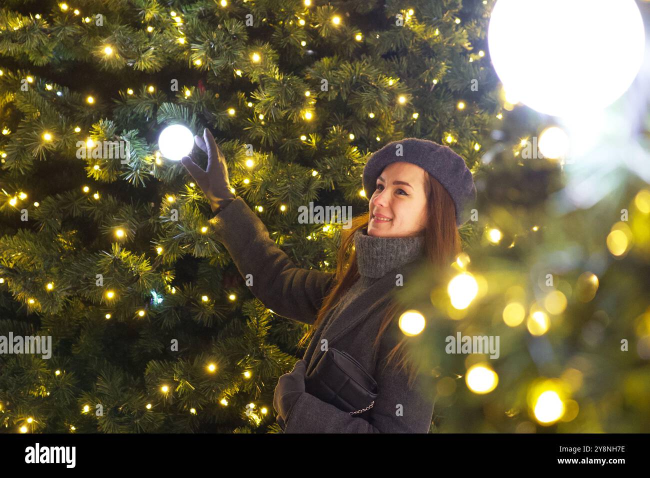 Stilvolle Pariser Frau im grauen Mantel blickt auf die Weihnachtsbaumdekoration Stockfoto