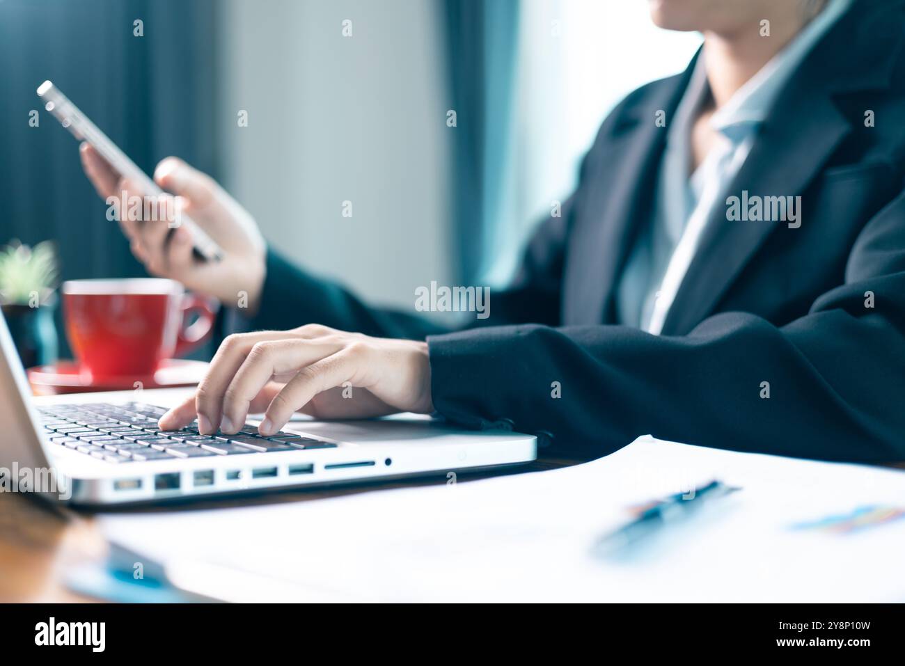 Frau sitzt am Tisch und nutzt ihr Mobiltelefon, um durch soziale Medien zu navigieren und Geschäfte mit den neuesten Technologien im Cyberspace zu tätigen. Social Media, Tisch Stockfoto