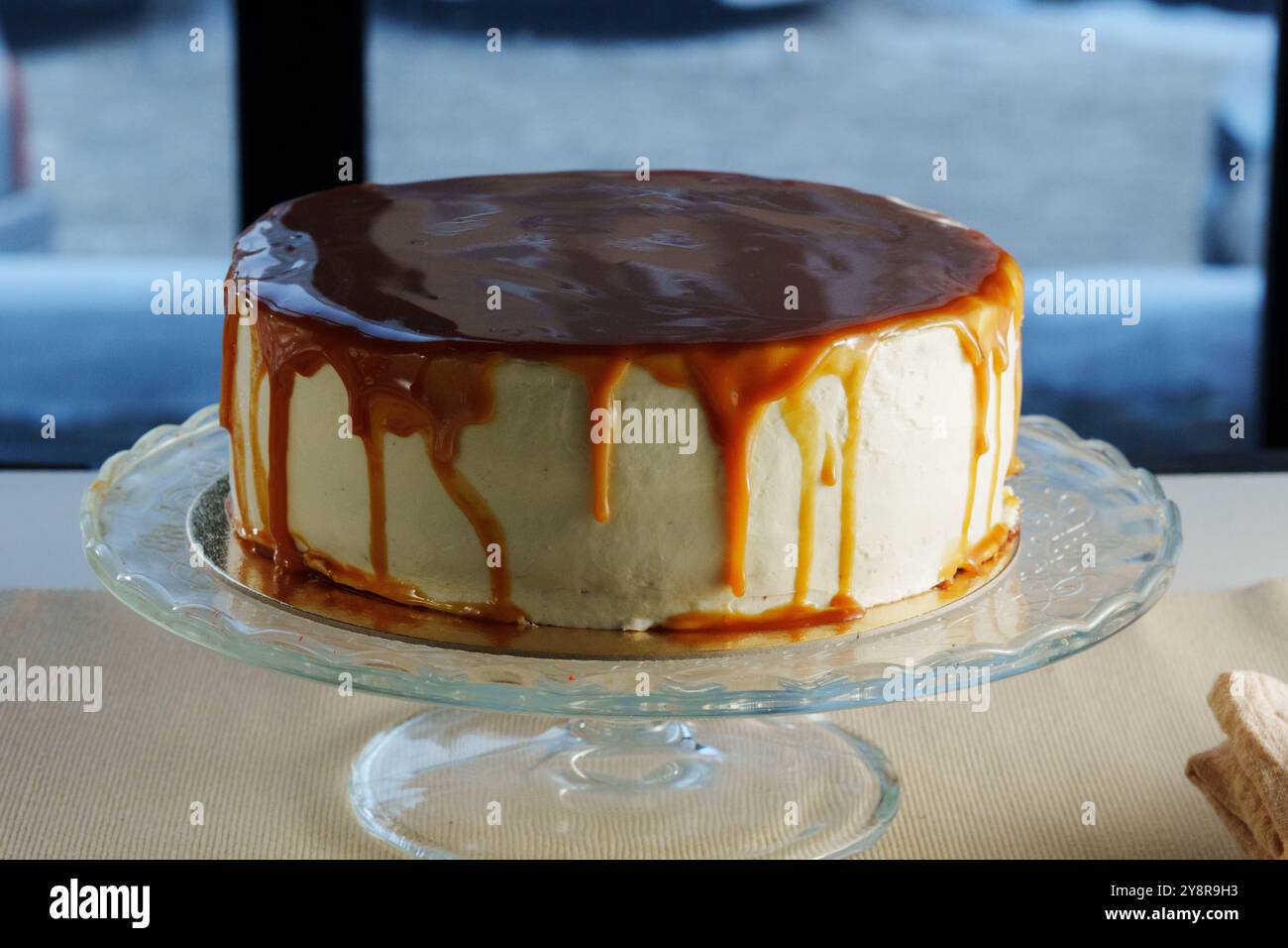 Feuchte Kuchenschichten werden großzügig mit glattem Karamell gekrönt, sodass der süße Nieselregen elegant kaskadiert und jeden zum Genießen einlädt. Stockfoto