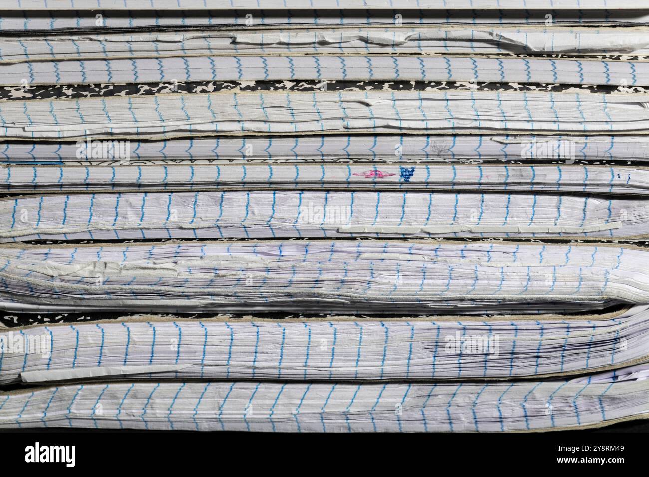 Nahaufnahme des Rückens abgenutzter Notizbücher, die die Alterung und Textur ihrer Seiten betont. Perfekt für Themen im Zusammenhang mit Studium und Schreiben. Stockfoto