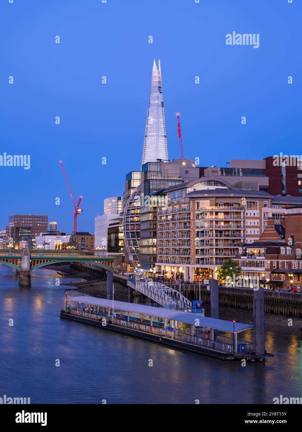 London, Großbritannien - 25. Juni 2024: Eine pulsierende Stadtlandschaft Londons mit modernen Wolkenkratzern entlang der Themse, blaue Stunden. Stockfoto