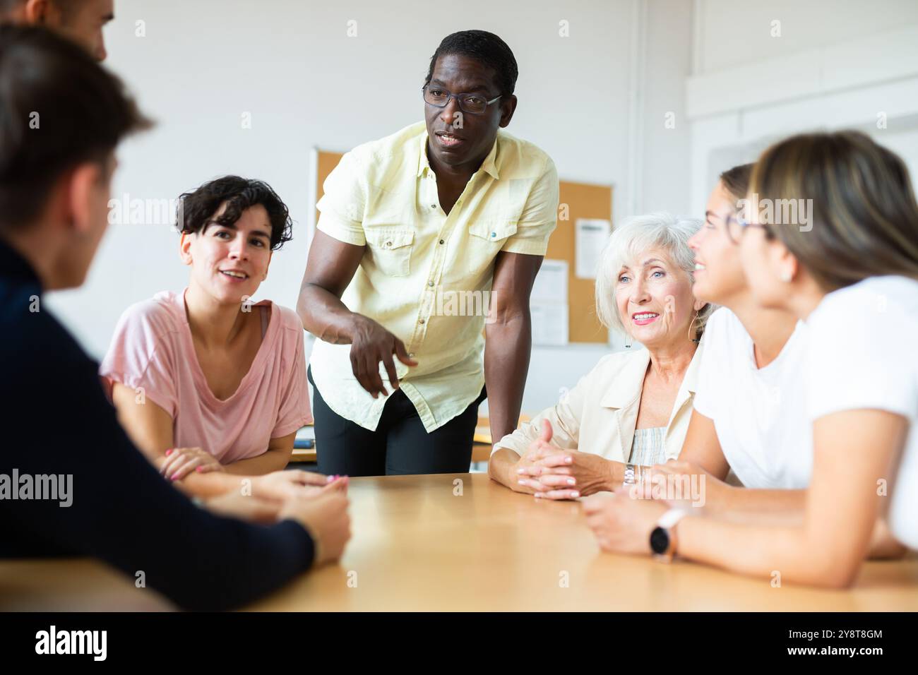 Freundliche afroamerikanische Englischlehrerin, die Sprachkurse für eine Gruppe von Erwachsenen gibt Stockfoto