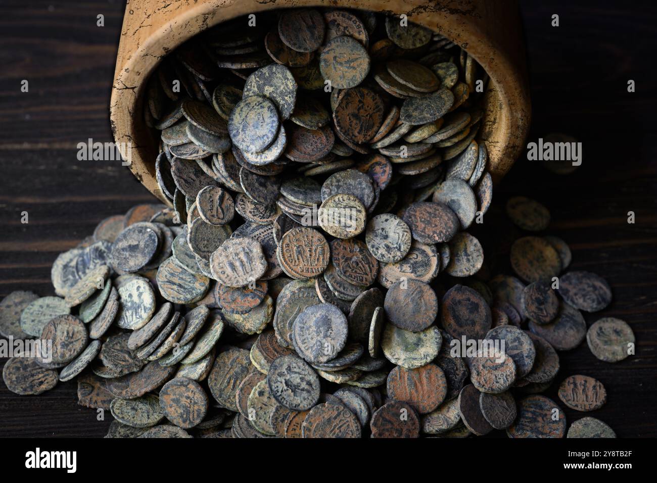 Römischer Münzhort auf dunklem Holztisch, viel altes Geld in altem Topf, Vintage Hintergrund. Das Konzept von Pile, Antique, Empire, Textur, Zivilisation und Stockfoto