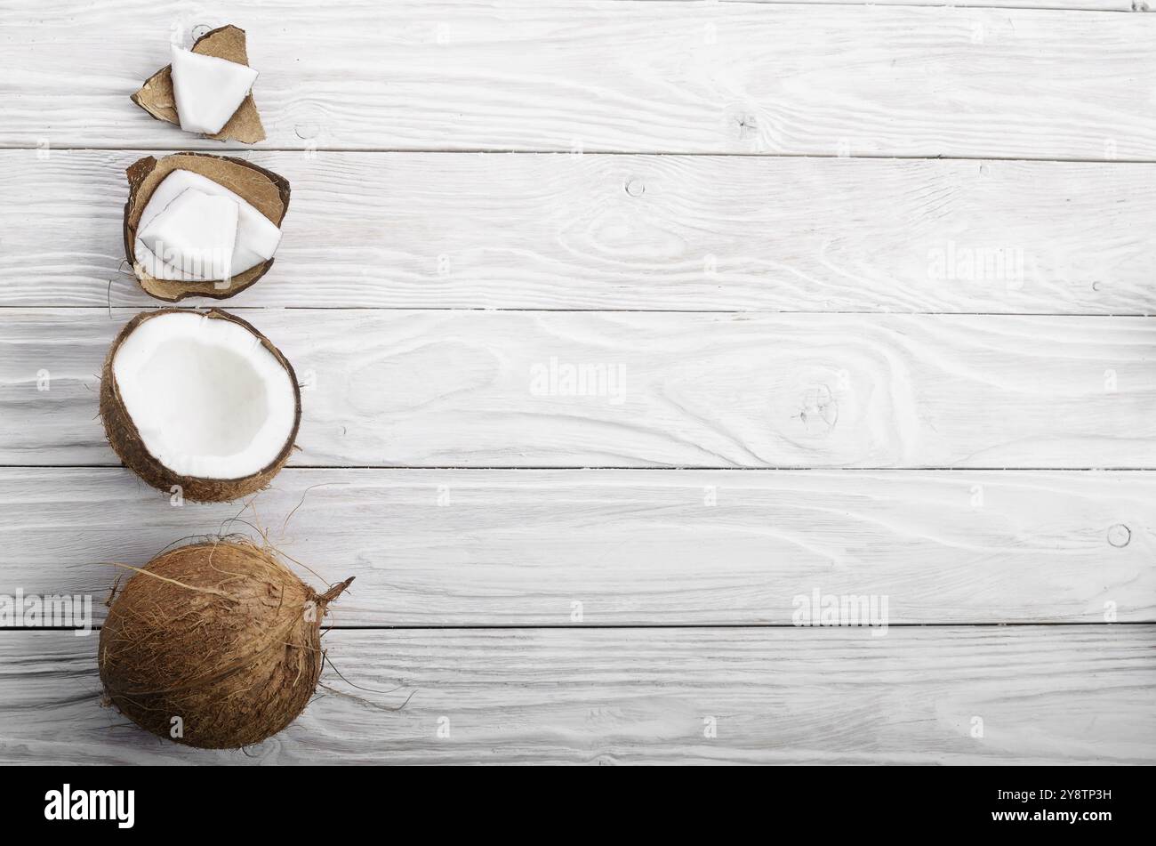 Flach Hintergrund der Kokosnuss, Kokosnussschalen und Fleischstücke auf weissem Holztisch Stockfoto